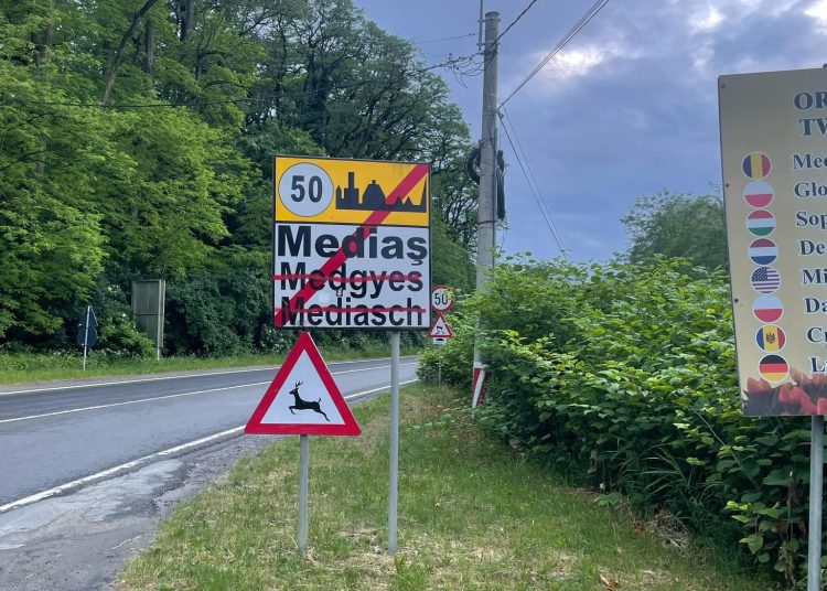 A képen Medgyes településtáblája látszik, amin pirossal áthúzták a magyar és német elnevezést.